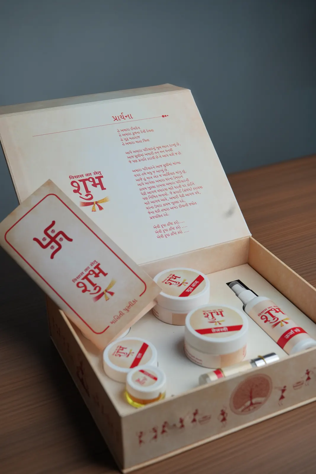The Shubh Kit, opened: a cream presentation box with the red शुभ emblem, holding jars of daily-ritual products, a spray and a printed blessing card
